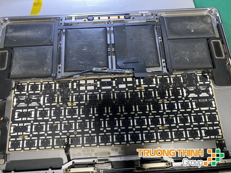 Kỹ thuật viên đang tháo bàn phím cũ bị hỏng ra khỏi MacBook cẩn thận