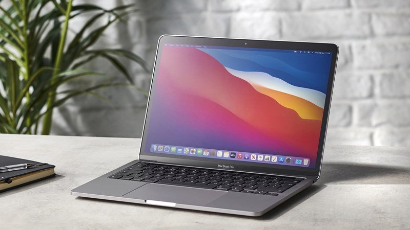 MacBook M1 màu bạc với logo Apple phát sáng, biểu tượng của máy tính xách tay cao cấp