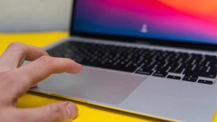 Một bàn tay đang thực hiện cách ấn chuột trái trên MacBook Trackpad