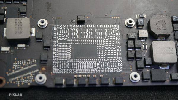 Một kỹ thuật viên đang làm sạch thiếc trên bo mạch chủ của MacBook sau khi gỡ CPU