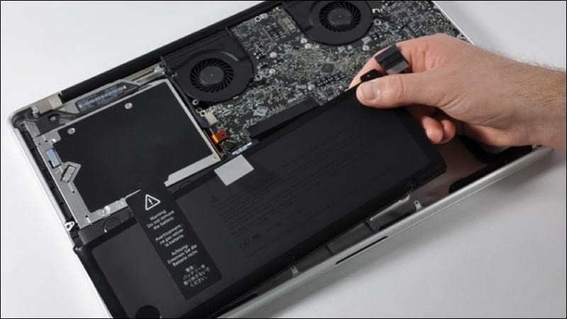 Người dùng đang tháo pin khỏi MacBook Pro để thực hiện quy trình reset SMC.